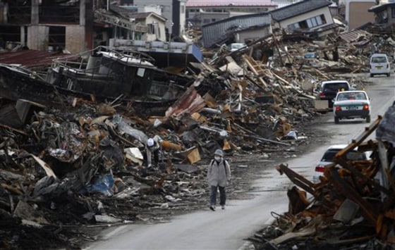 A resident walks between the rubble caused by the March 11 tsunami at Kesennuma, Miyagi Prefecture, northern Japan, on Wednesday.